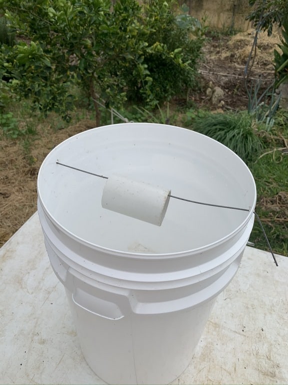 Here is the bucket with wire through the two drilled holes and the pvc pipe threaded onto the wire